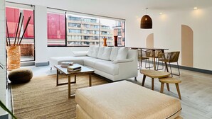 A modern living room with a white sofa, a coffee table, and a dining area with chairs and a small table. - Chicala By Wynwood House (Bogotá)