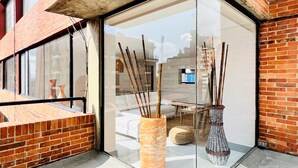 A glass door entrance to a room with a brick exterior, a tiled floor, and a view of a cityscape through the glass. - Chicala By Wynwood House (Bogotá)