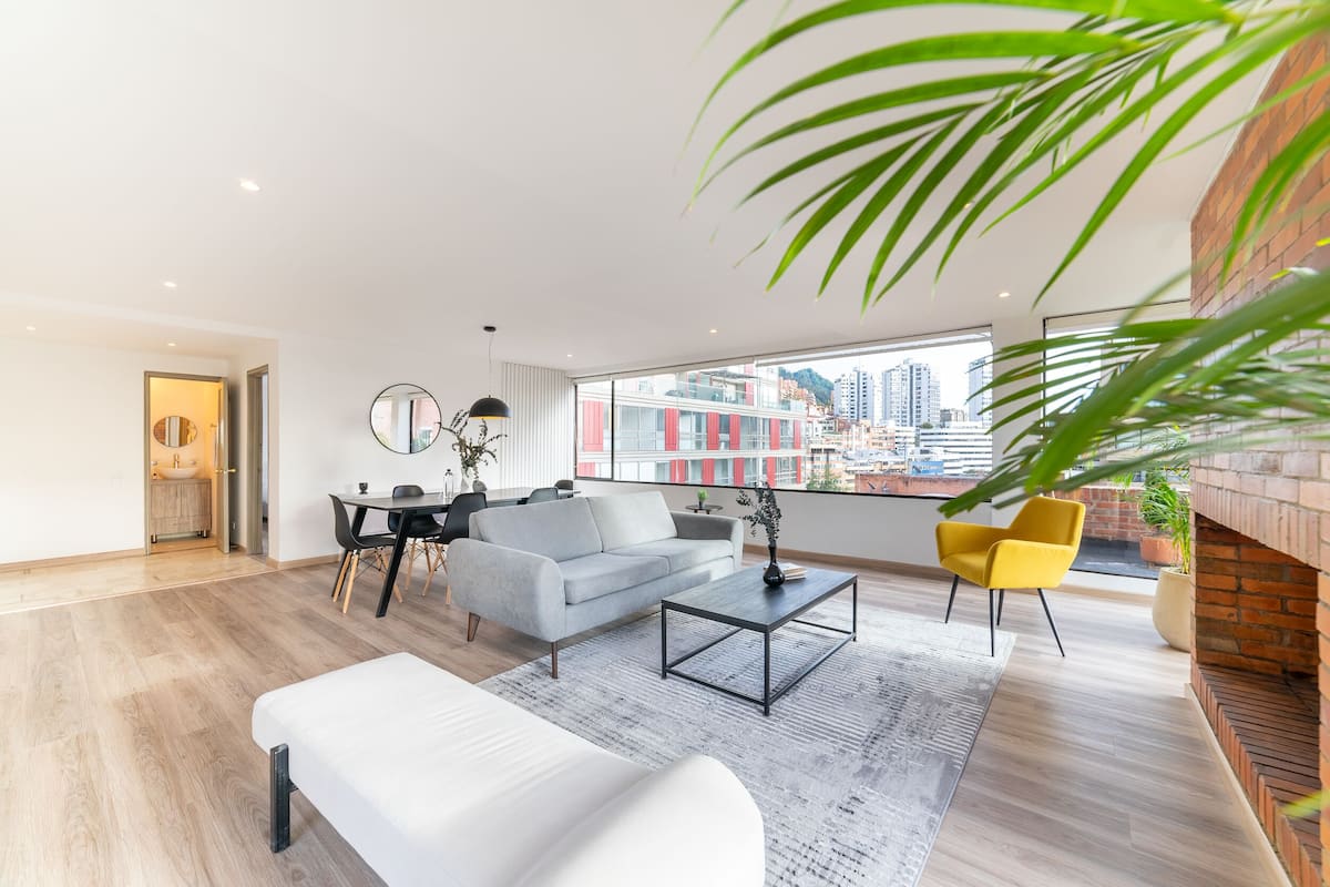 A modern living room with a sofa, coffee table, and a dining area.