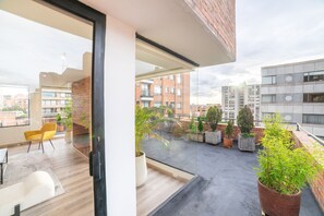Een modern appartement met een balkon, grote ramen en plantenbakken.