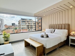 Een moderne slaapkamer met een groot raam, een bed, een nachtkastje en een bankje.