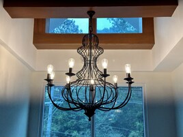 Um candelabro com várias lâmpadas em um quarto com uma janela grande.
