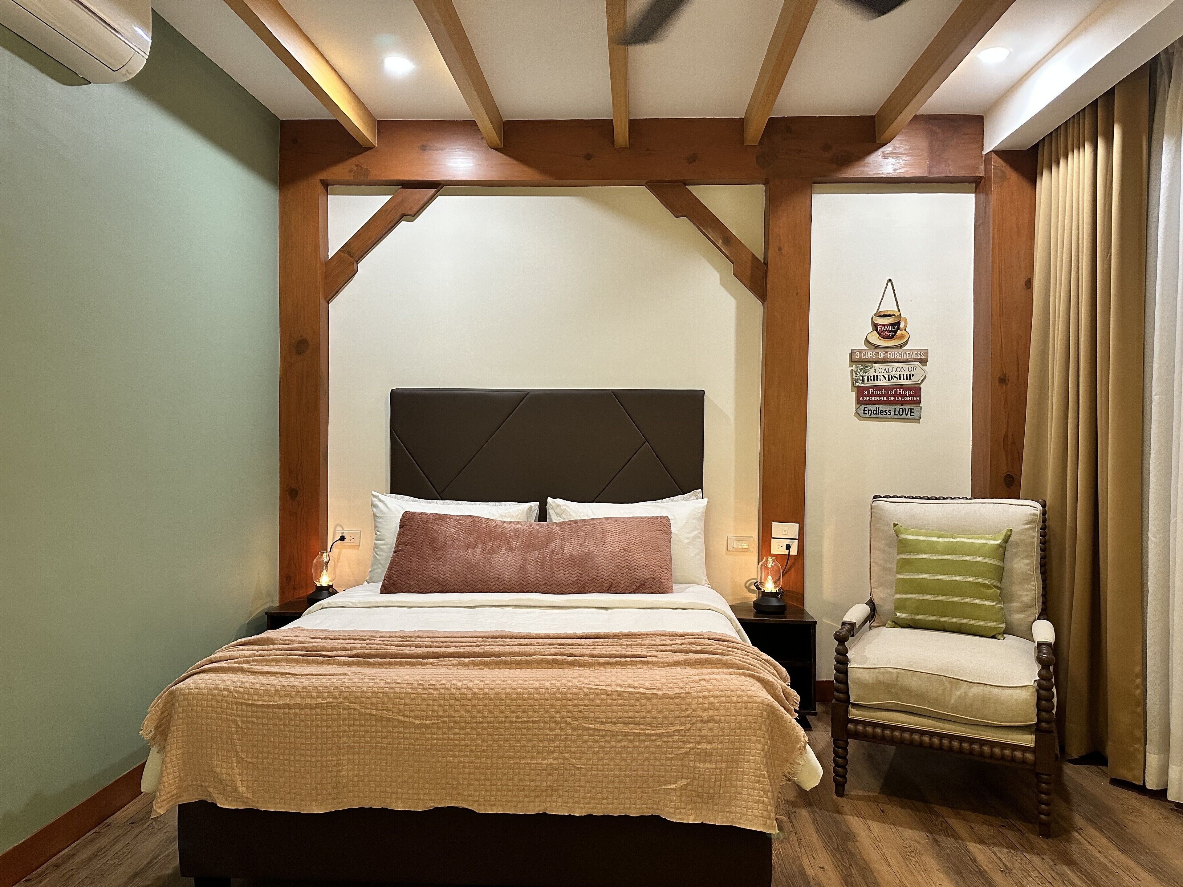 A bedroom with a large bed, a wooden headboard, a nightstand, a chair, and a wall-mounted light fixture.