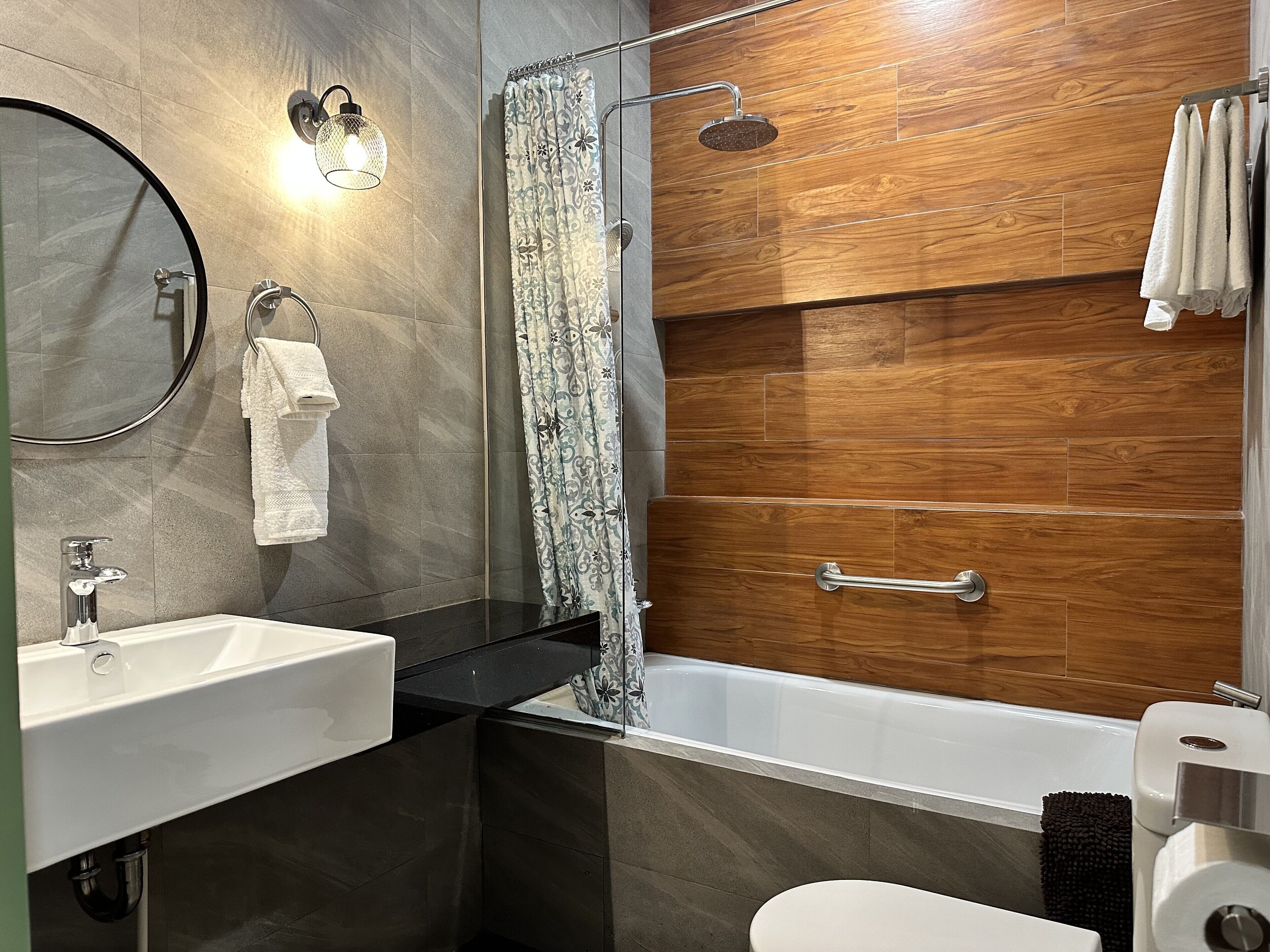A modern bathroom with a bathtub, a shower, a sink, and a toilet.