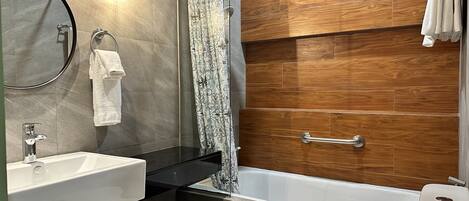 A modern bathroom with a bathtub, a shower, a sink, and a toilet.