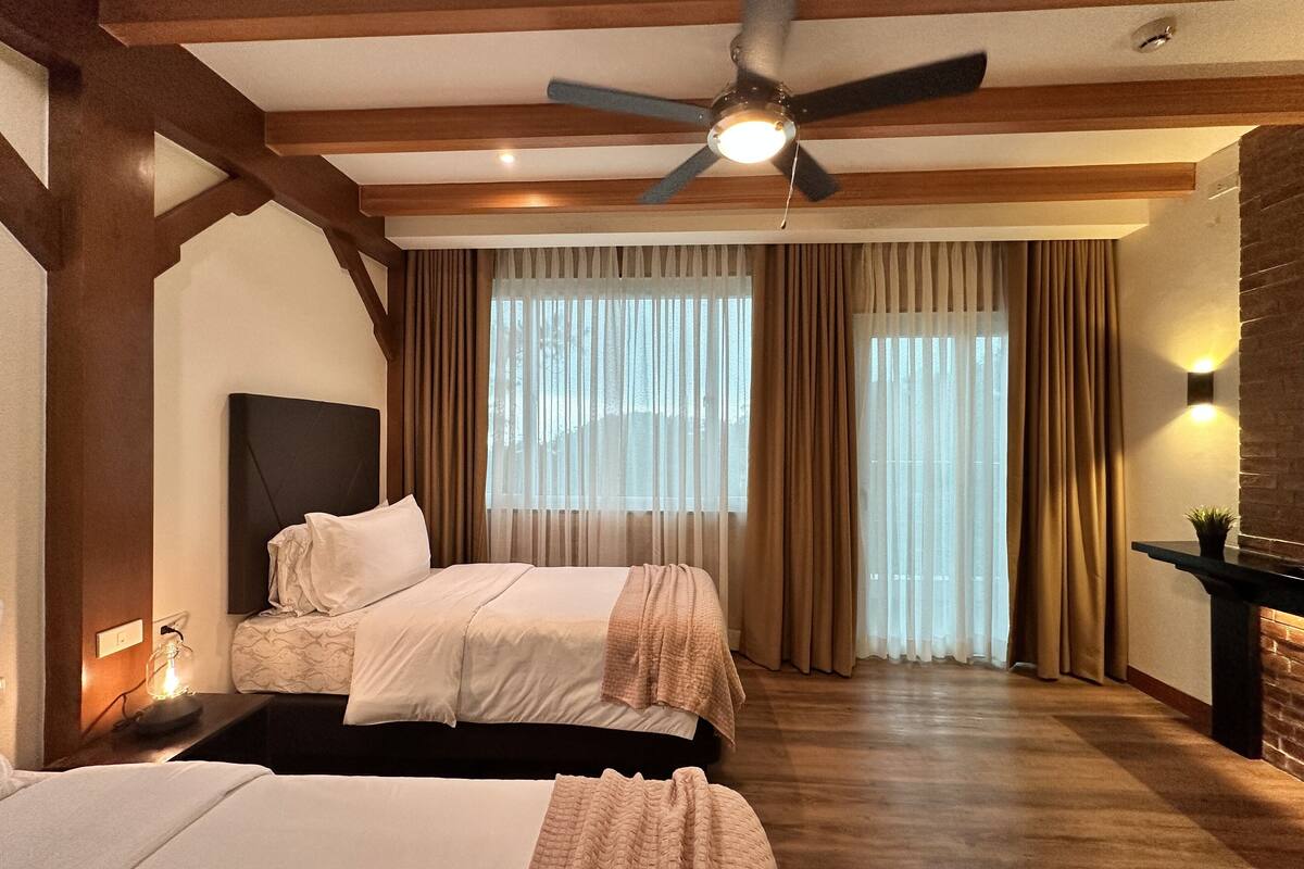 A hotel room with a large bed, a ceiling fan, and a fireplace.