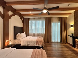 Une chambre d’hôtel avec un grand lit, un ventilateur de plafond et une cheminée.