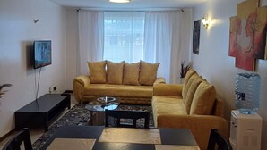 Una sala de estar con sofá, mesa de centro, televisor y un comedor con mesa y sillas.