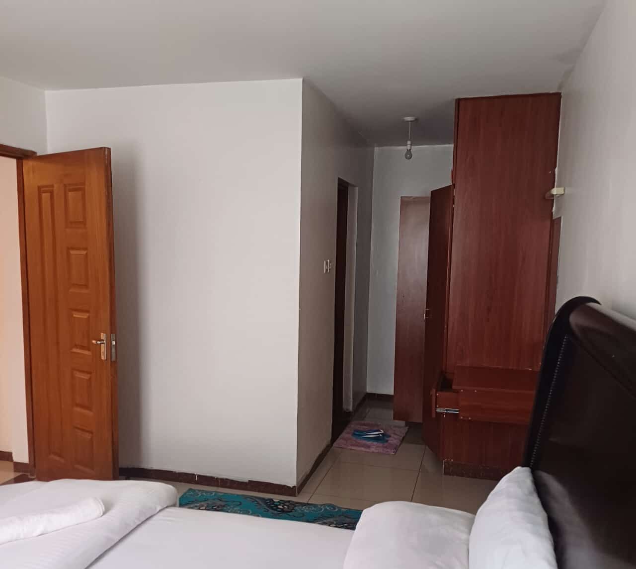 Hotellihuone, jossa on sänky, vaatekaappi ja ovi.