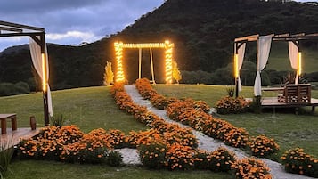 A garden with a pathway lined with orange flowers leading to a wooden archway.