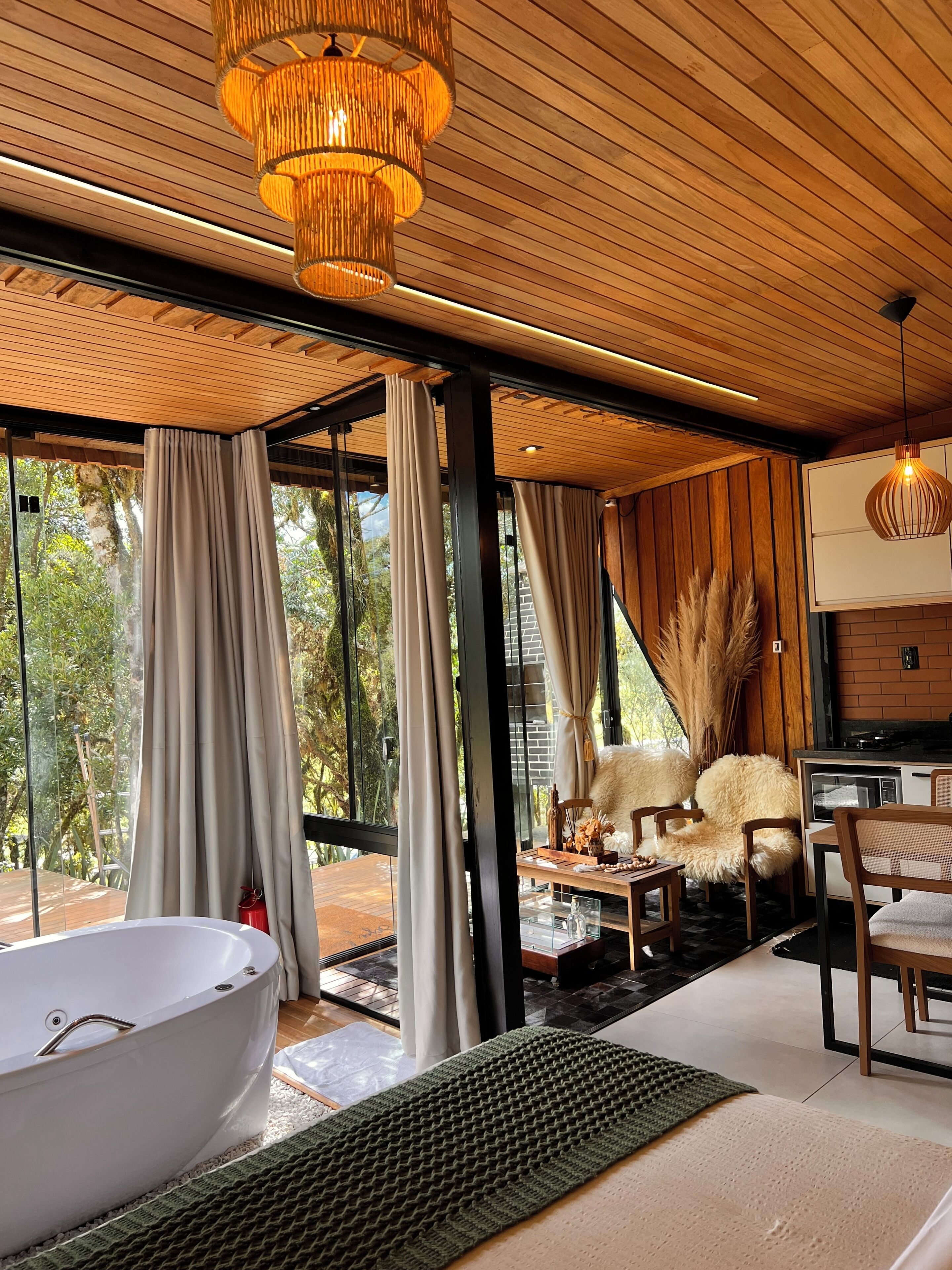 Ein modernes Interieur mit einer großzügigen Badewanne, Holzboden und großen Fenstern mit Blick auf Grünflächen.