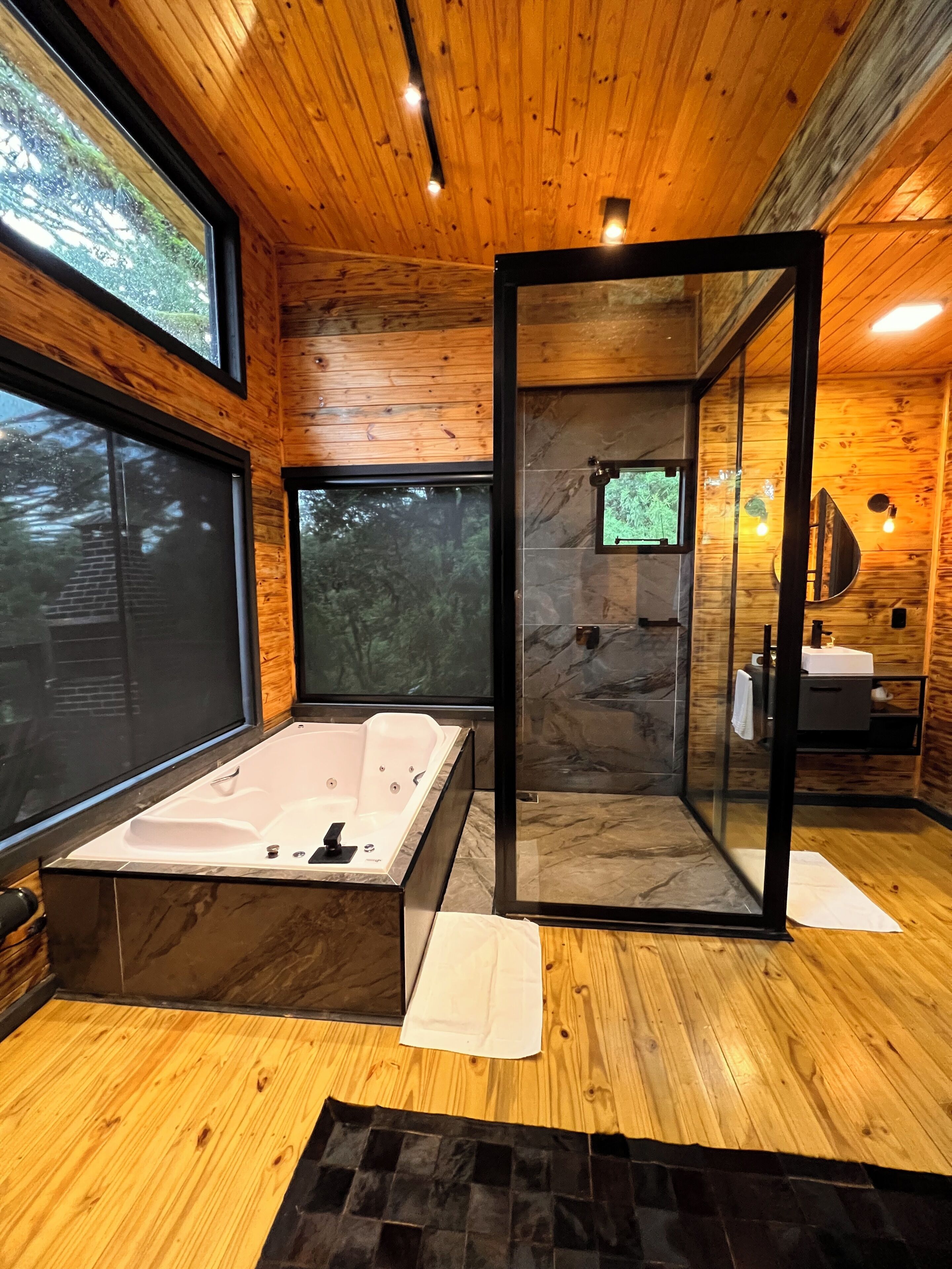 A modern bathroom with a large bathtub, a glass-enclosed shower, and a wooden interior.