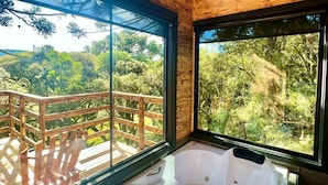 Une cabane en bois dotée d’une grande fenêtre et d’un bain à remous.
