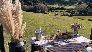 Un coin pique-nique aménagé avec une table, de la nourriture et une vue sur un paysage verdoyant et des collines.