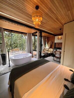 Een moderne slaapkamer met een groot bed, een vrijstaand bad, een eethoek en een keuken.