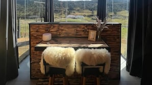 Une pièce dotée d’un plafond haut et de grandes fenêtres offrant une vue sur les montagnes. On y trouve un bureau en bois avec deux chaises et un tapis moelleux.