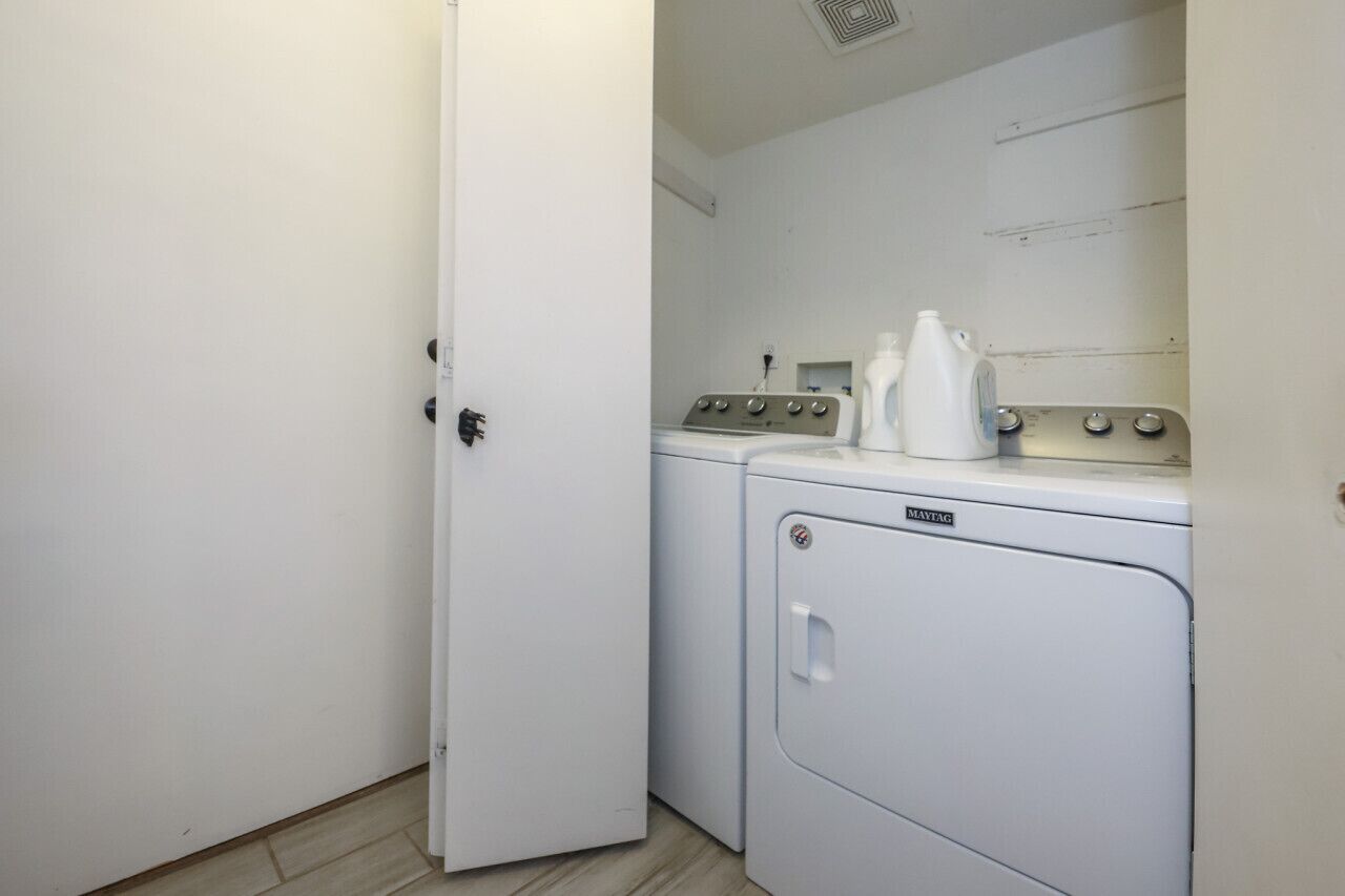 Une buanderie avec une porte blanche, un lave-linge et un sèche-linge.