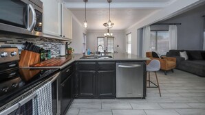 Una cocina moderna con una isla central, electrodomésticos de acero inoxidable y un área de comedor con sofá y sillas.