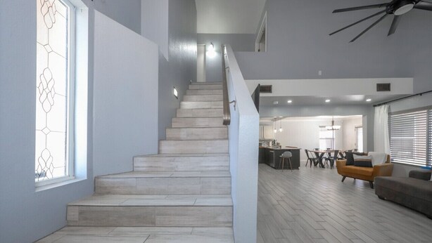 Una escalera conduce a un segundo piso con una decoración moderna, que incluye un comedor y asientos.