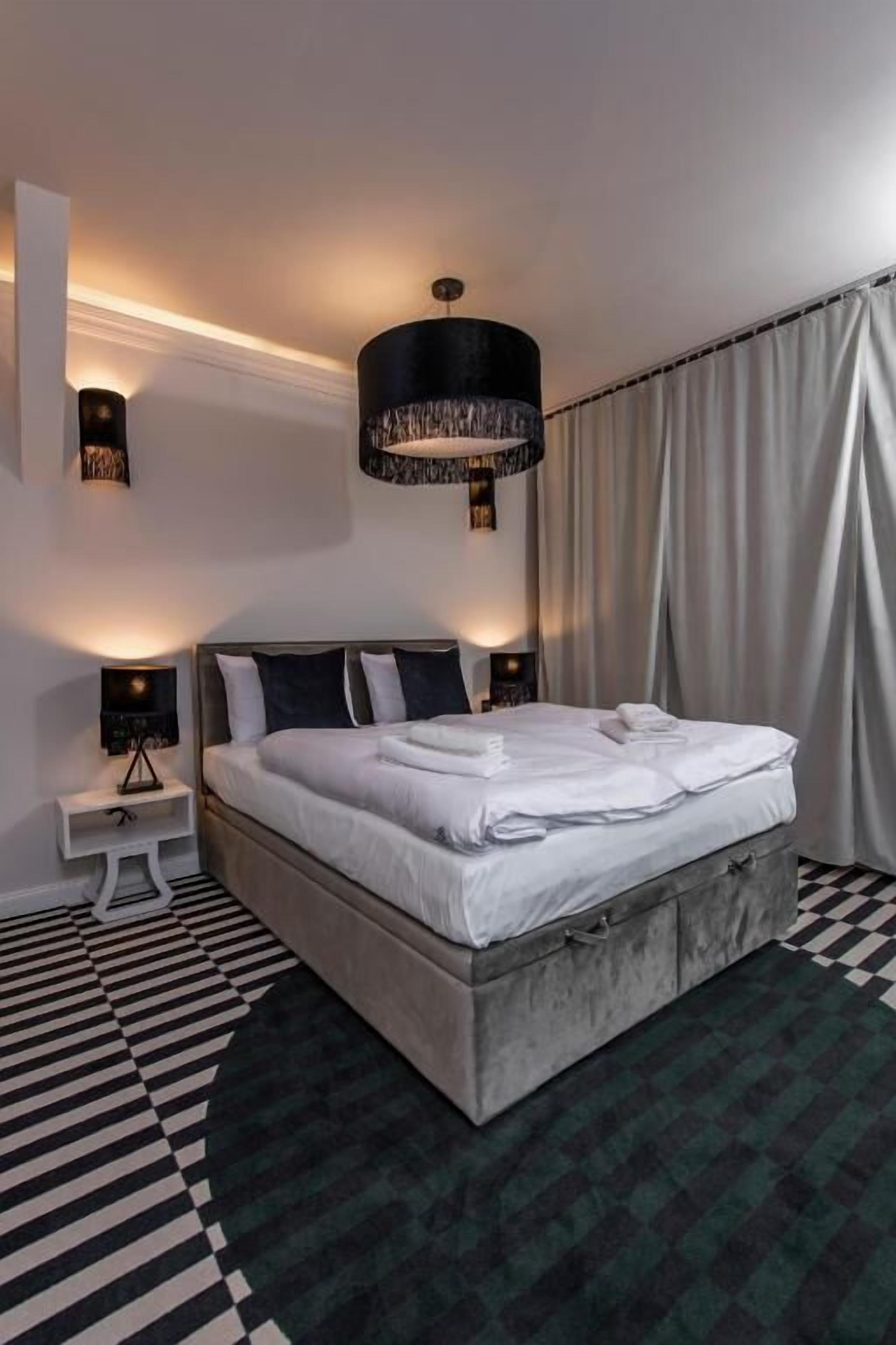 A modern bedroom with a large bed, a round rug, and a pendant light.