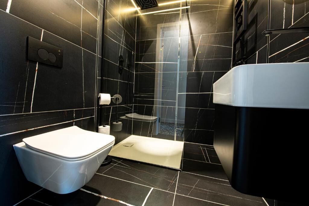 Une salle de bain moderne équipée de toilettes, d’un bidet et d’un espace douche.