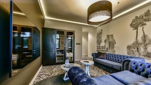 A modern hotel lobby with a zebra-patterned carpet, a blue sofa, a round coffee table, and a large mirror. - Fregata Kołobrzeg (Kolobrzeg)