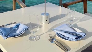 Une table dressée pour deux personnes, avec vue sur la mer et les îles au loin.