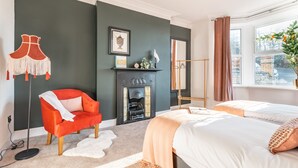 Een moderne slaapkamer met een open haard, een rode fauteuil, een bed en uitzicht op de stad door een raam.