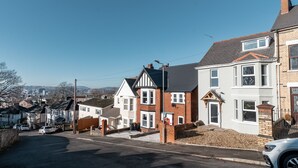 Een woonstraat met huizen, een heldere lucht en een verafgelegen stadsgezicht.