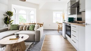 Een moderne keuken met witte kasten, een houten aanrechtblad en een inbouwoven.