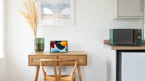 Een keuken met een houten tafel, een tablet, een magnetron en een vaas met gedroogde planten.