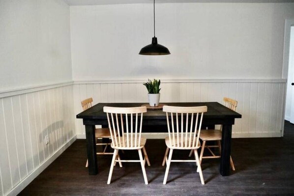 A dining area with a dark wooden table and two light wooden chairs.