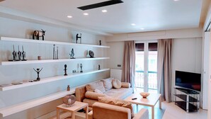 A modern living room with a sofa, coffee table, and shelves with decorative items. - Luxurious minimal apartment in Acropolis (Athina)