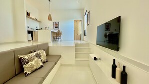 A modern living room with a sofa, a TV mounted on the wall, and a staircase leading to another room. - Casa com Piscina Privativa e Hidromassagem #2 (Tibau do Sul)