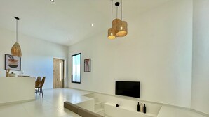 A modern living room with a large white sectional sofa, a flat-screen TV, and a dining area with a wooden table and chairs. - Casa com Piscina Privativa e Hidromassagem #2 (Tibau do Sul)