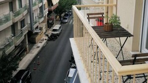 Vista de uma varanda com vista para a rua, onde se veem carros estacionados e edifícios.