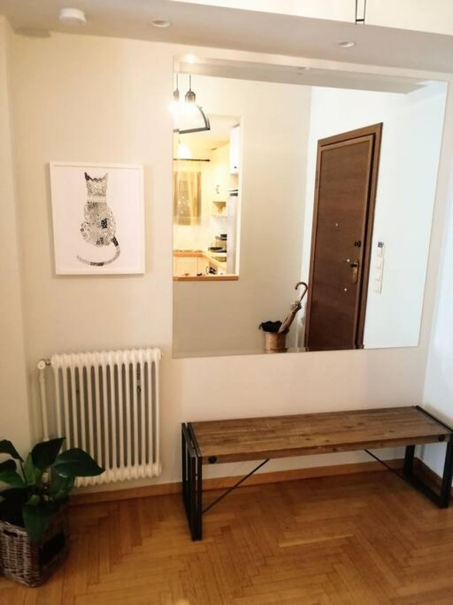 A room with a wooden bench, a radiator, a framed cat illustration, and a door.