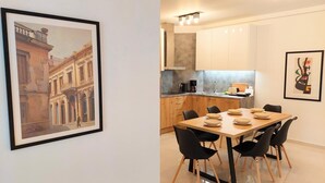 A modern kitchen with wooden cabinets, a dining table set with plates, and a coffee machine. - Wonderful apartment in Acropolis (Athina)
