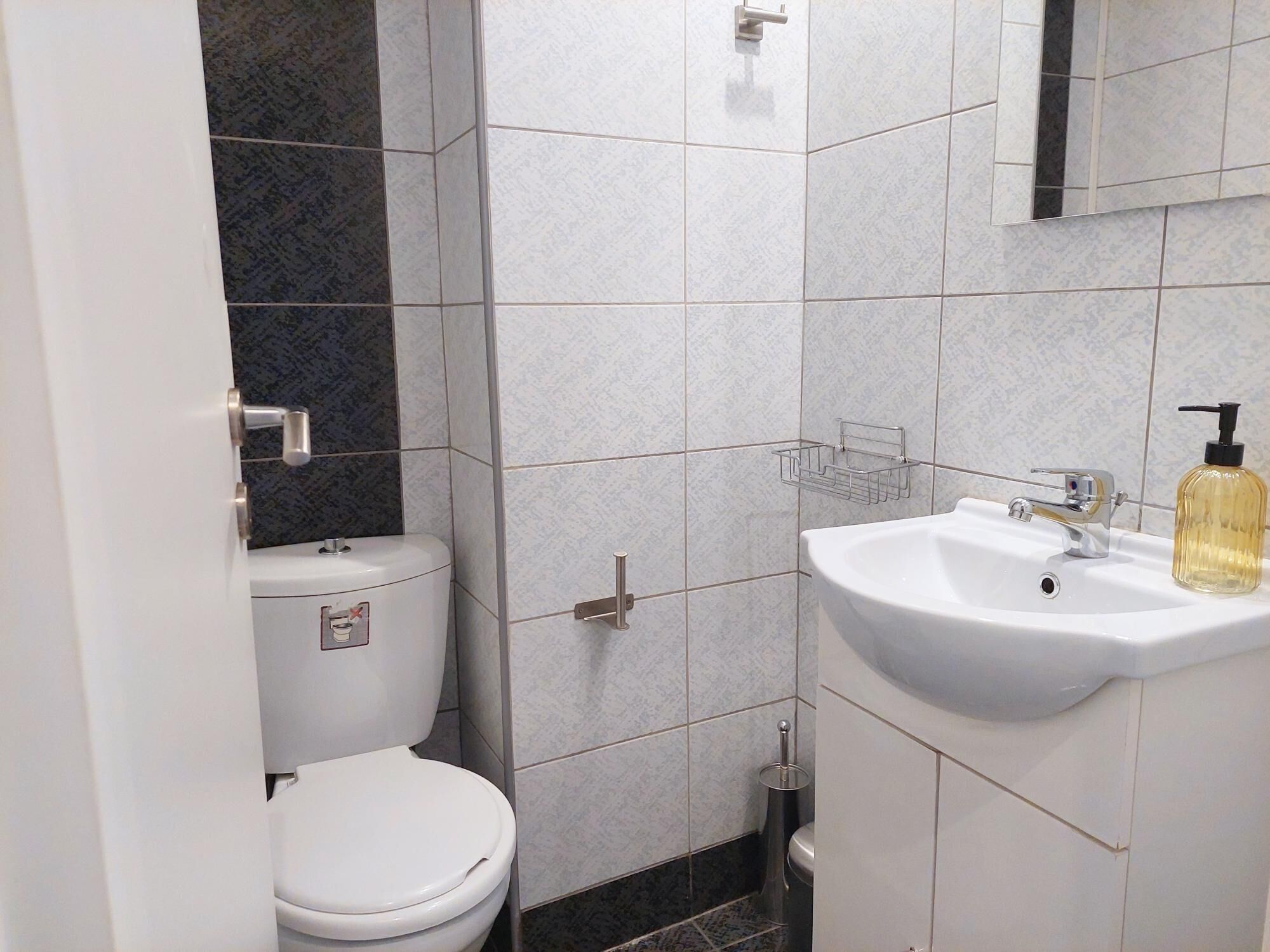 A compact bathroom with a toilet, sink, and mirror.