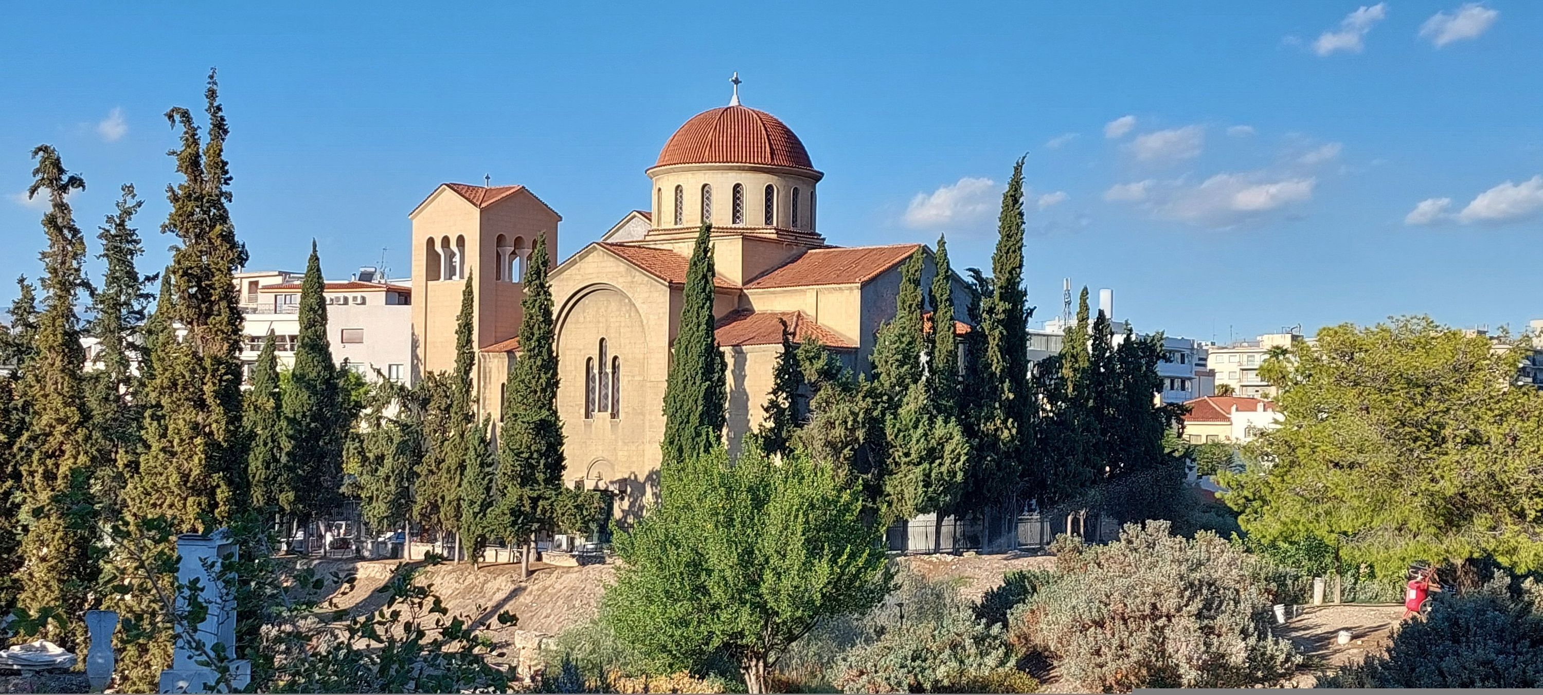 A church with a prominent dome and bell tower, surrounded by trees and buildings.