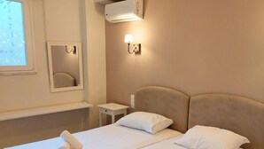 A hotel room with two beds, a bedside table, a mirror, and an air conditioning unit. - Charming Acropolis view apartment (Athina)