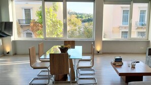 A modern living room with a glass dining table, wooden chairs, a grey sofa, and a coffee table. - Charming Acropolis view apartment (Athina)