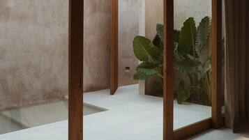 Un intérieur moderne au design minimaliste, agrémenté d’une grande plante, d’un miroir à cadre en bois et d’un espace épuré et dégagé.