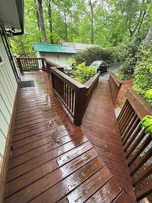 A wooden deck with a metal railing, surrounded by greenery. - Cozy mtn retreat near Grandfather MTN and skiing! (Newland)