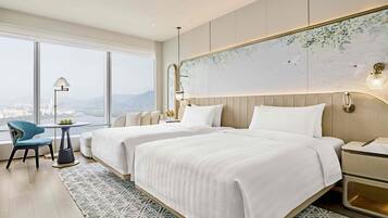 A hotel room with two beds, a view of the city, and a large window.
