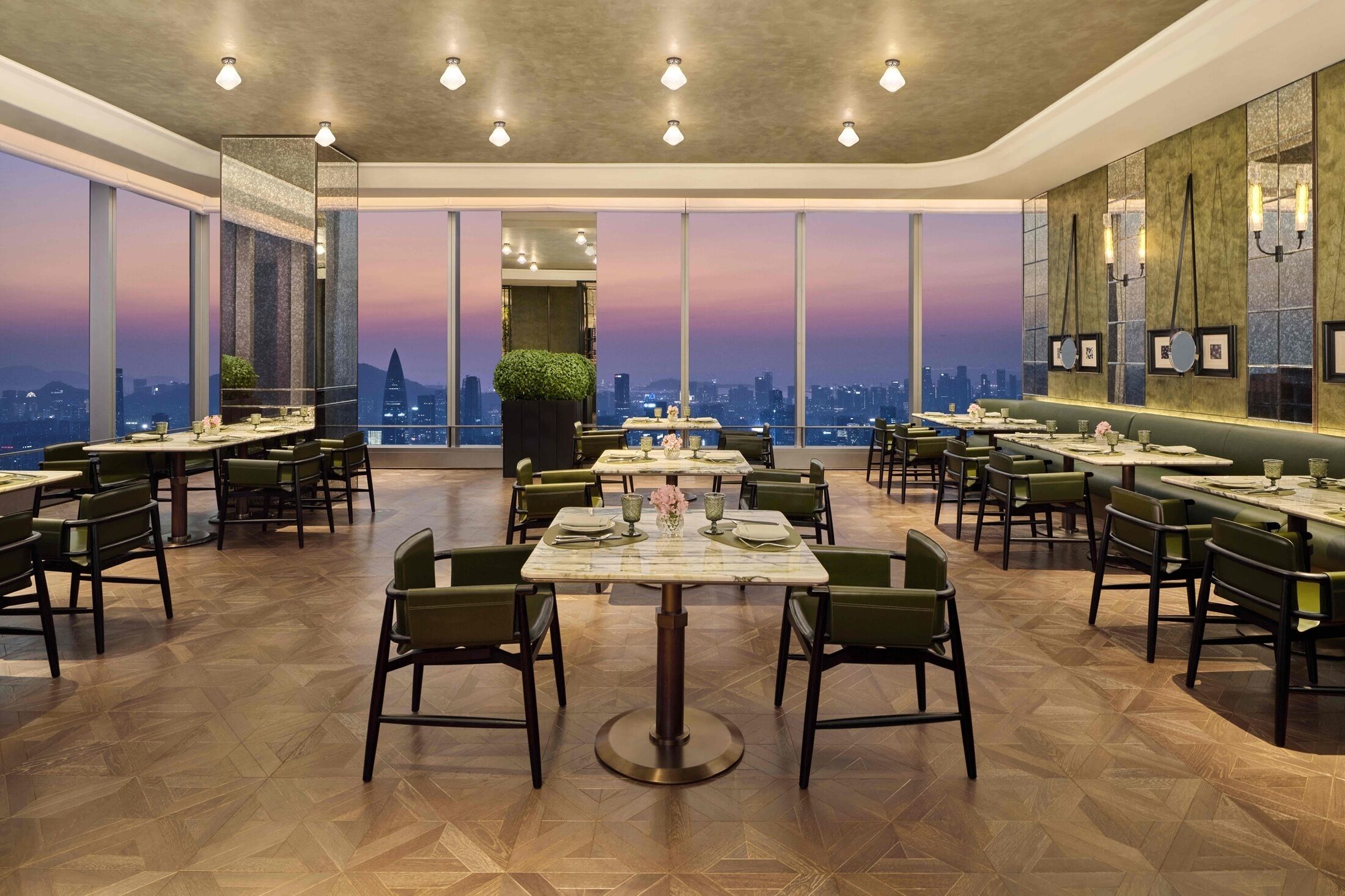 A restaurant with multiple tables and chairs, large windows with a city view, and a modern interior design.