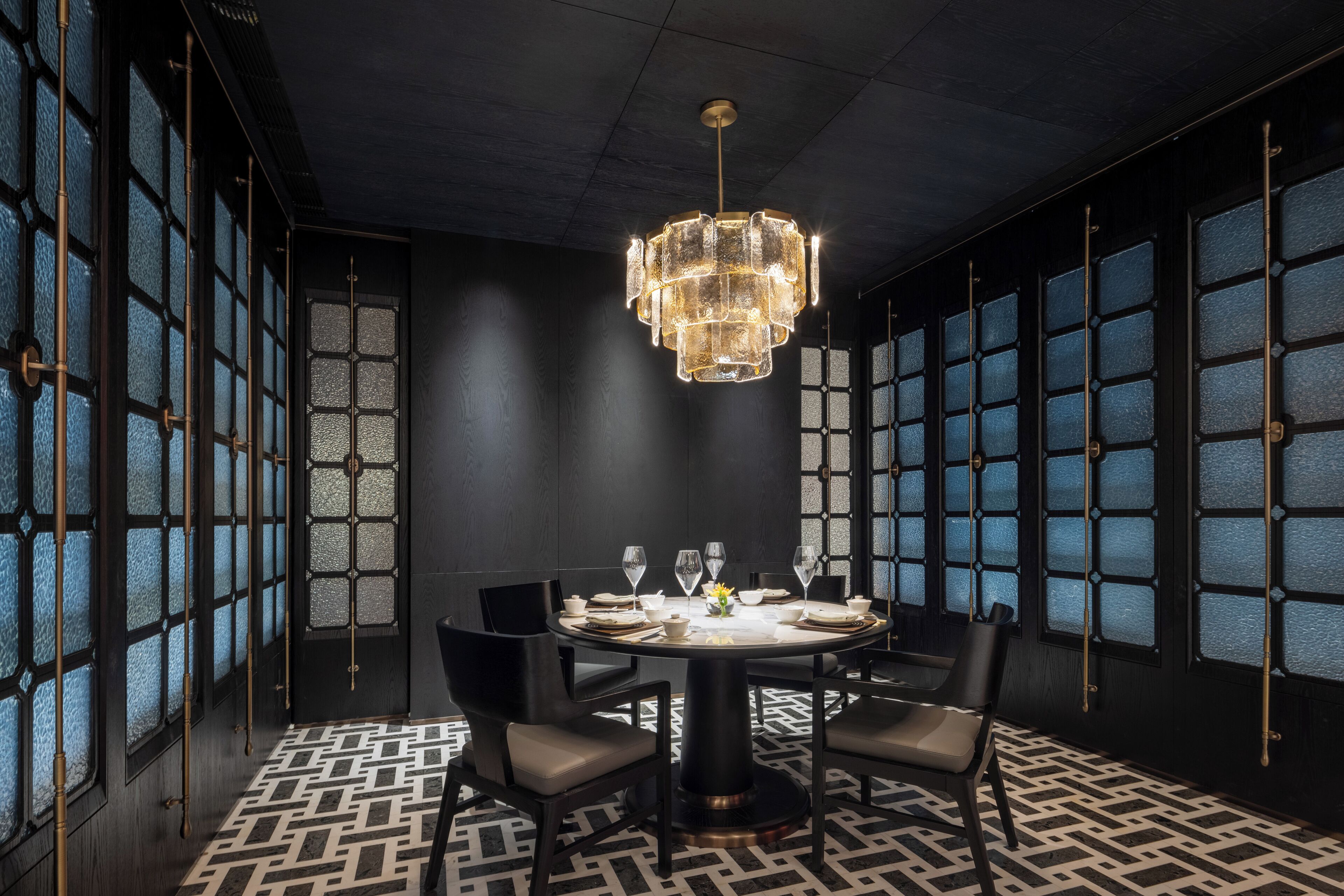 A dining area with a round table, chairs, and a chandelier.