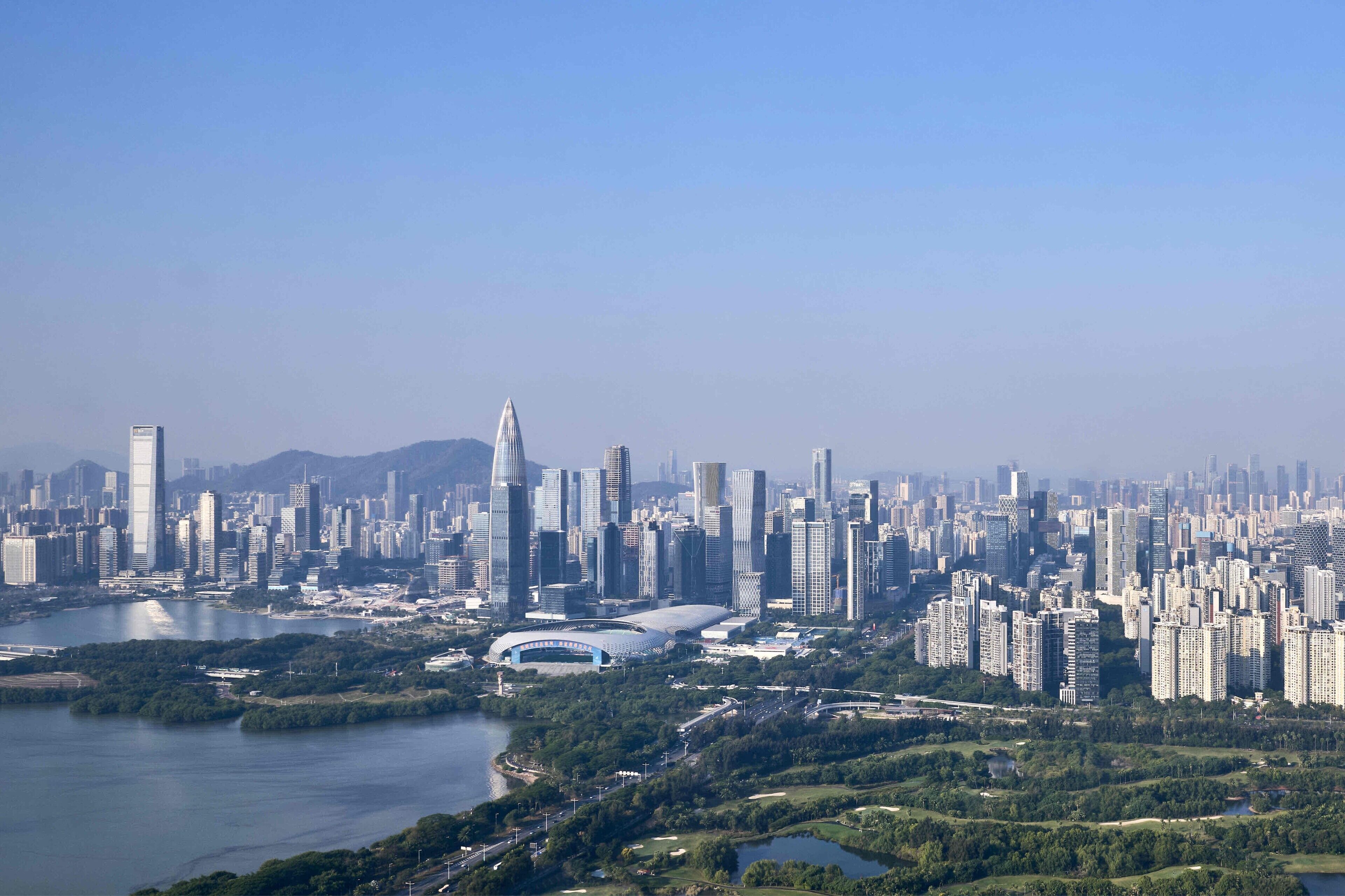 A cityscape with a river, high-rise buildings, and a stadium.
