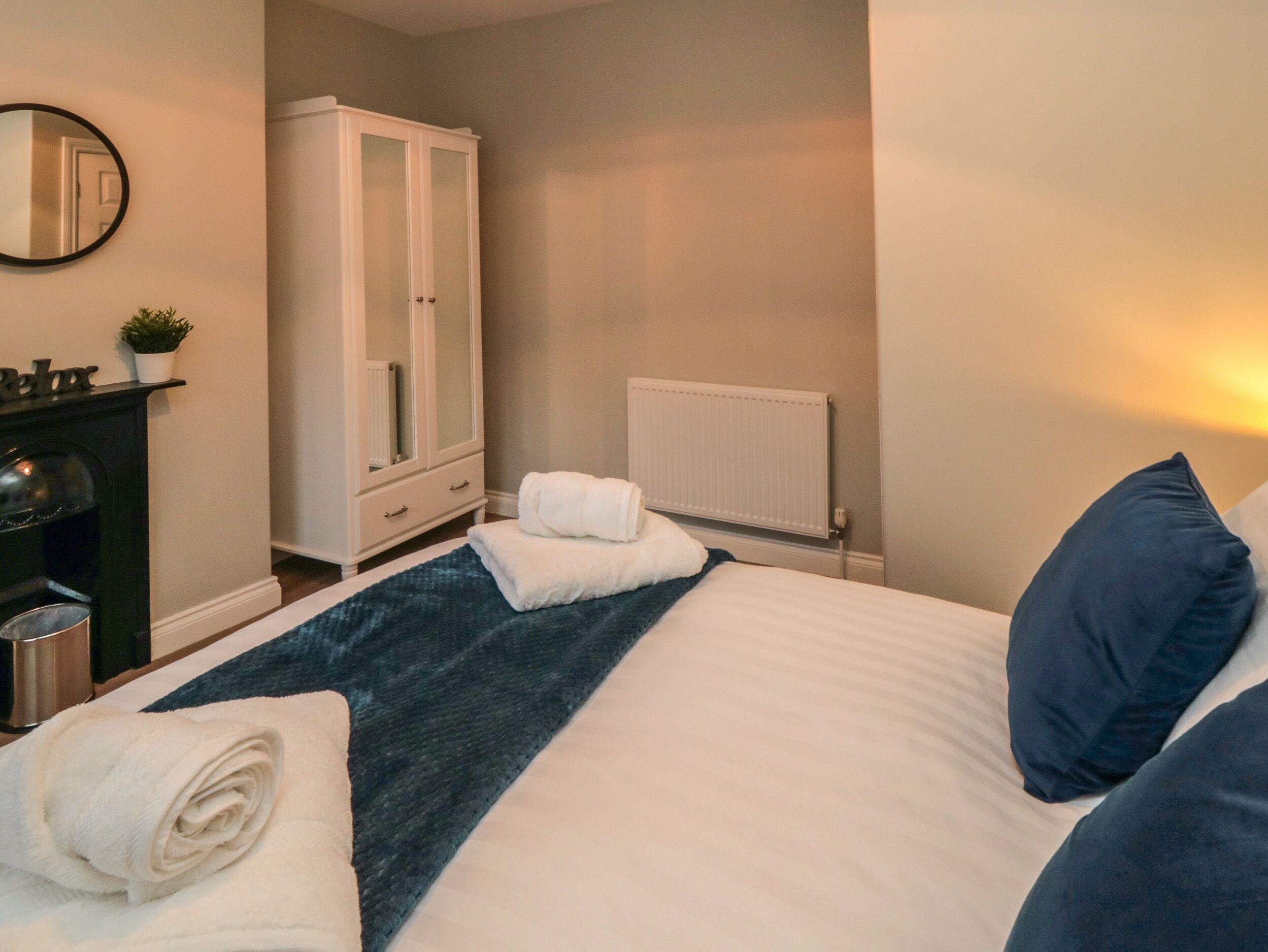 A bedroom with a bed, a wardrobe, a radiator, and a mirror on the wall.