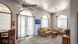 A spacious living room with two sofas, a wooden coffee table, and a dining area with a wooden table and chairs. - Sandcastle Sunset view Ocean front apartment with pool (San Pedro)